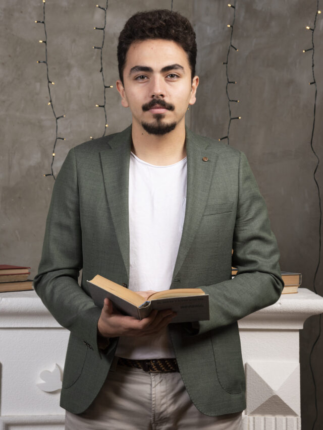 Portrait of young bearded man reading book